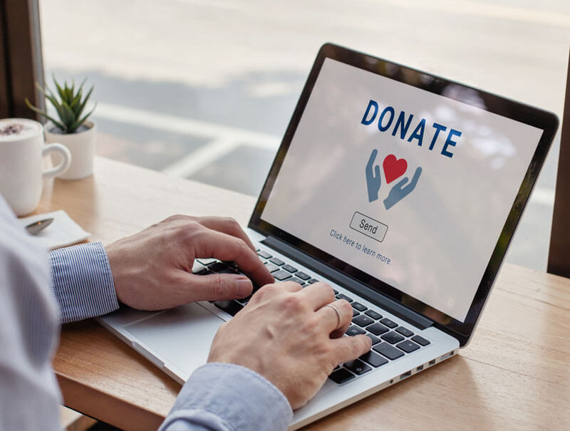 A person typing on a laptop to make an online donation