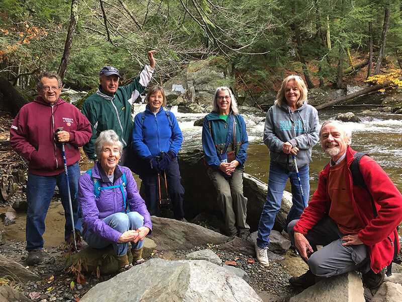 Group of Hikers Seven Community Senior Center members sitting on rocks along a river