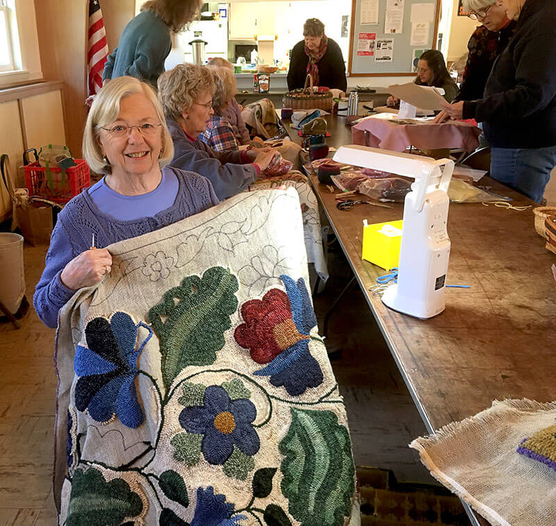 Woman happily showing her rug making work