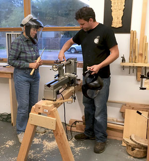 Two people learning in a workshop to use a lathe